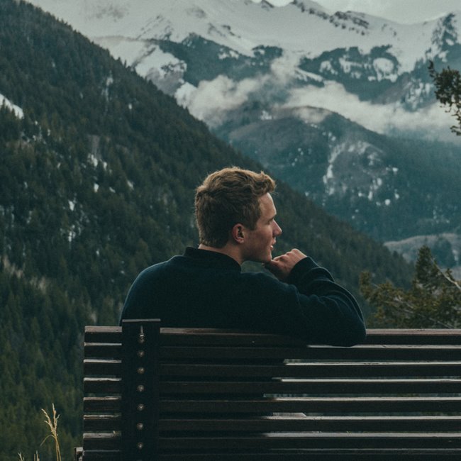 man on bench with mountain view